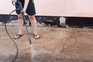 Worker cleaning dirty floor with high pressure washer